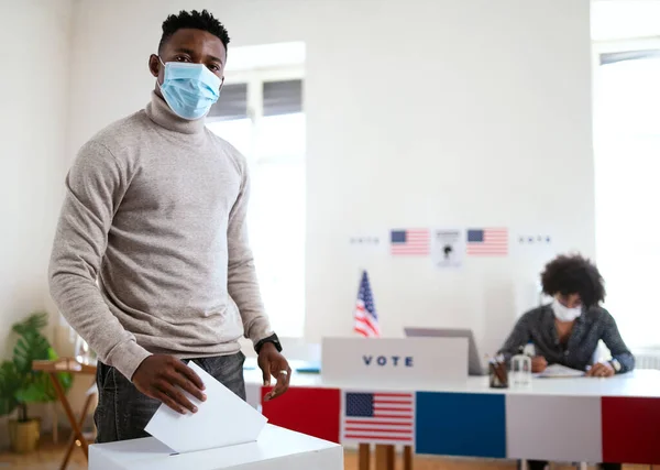Афро-американец кладет свой голос в урну для голосования, сша выборы и коронавирус. — стоковое фото