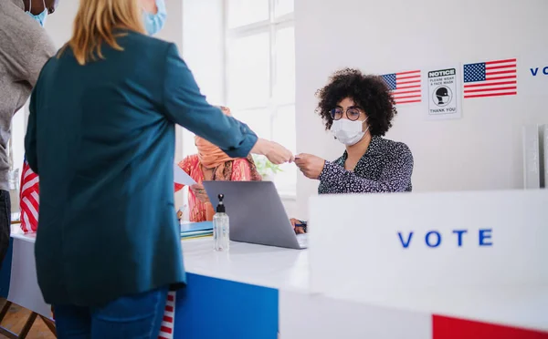 Personas con máscara facial votando en el lugar de votación, elecciones a EE.UU. y coronavirus. — Foto de Stock