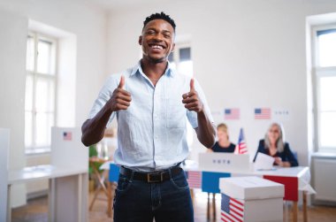 Mutlu Afro-Amerikalı adam seçim bölgesinde kameraya bakıyor..
