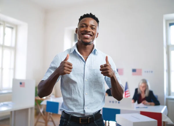 Happy african-american man looking at camera in the polling place, usa elections.