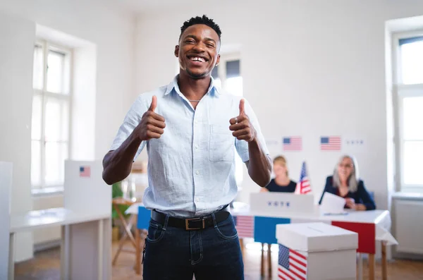 Happy african-american man looking at camera in the polling place, usa elections.