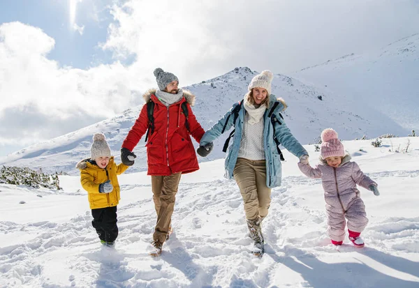 Far och mor med två små barn i vinternaturen, vandrar i snön. — Stockfoto