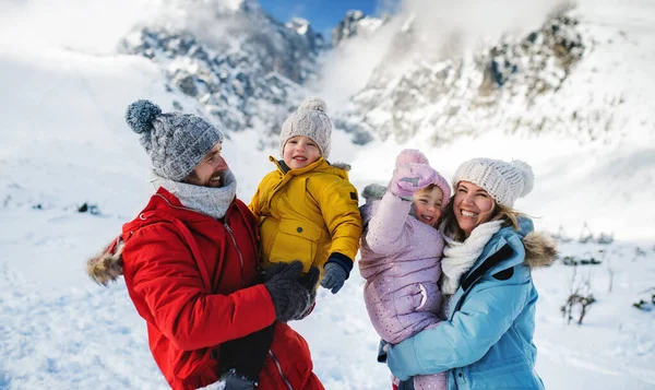 Pai e mãe com dois filhos pequenos na natureza de inverno, de pé na neve. — Fotografia de Stock