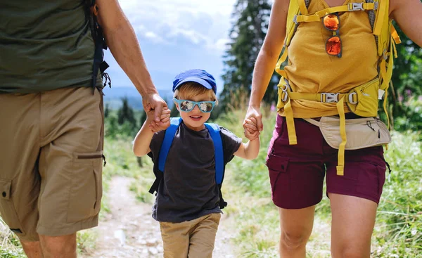 Front view of small boy with unrecognizable parents hiking outdoors in summer nature. — Stock Photo, Image