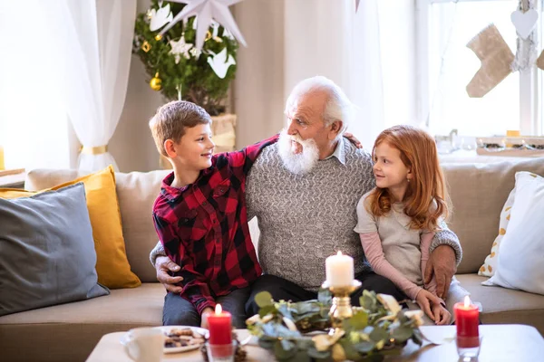 Crianças pequenas com avô sênior em casa no Natal, conversando. — Fotografia de Stock