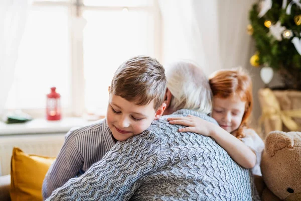 Kleine Kinder mit Großvater zu Weihnachten zu Hause und umarmen sich. — Stockfoto