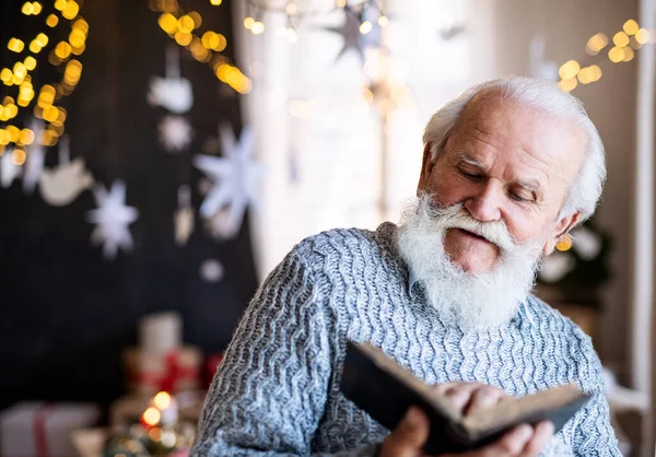 Frontansicht eines glücklichen Seniors zu Weihnachten zu Hause, der Buch liest. — Stockfoto