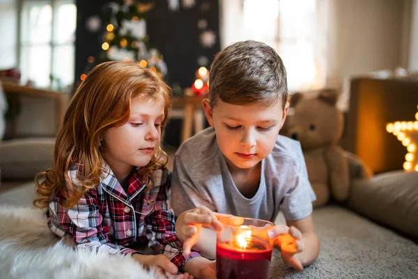 Mała dziewczynka i chłopiec w domu w Boże Narodzenie, trzymając świecę. — Zdjęcie stockowe