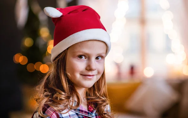 Portret dziewczynki w kapeluszu Mikołaja w domu na Boże Narodzenie, aparat fotograficzny. — Zdjęcie stockowe