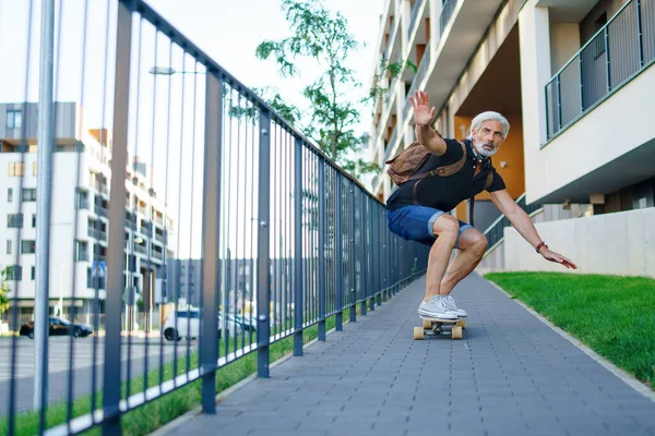 Portrét dospělého muže na skateboardu venku ve městě, vracející se do práce. — Stock fotografie