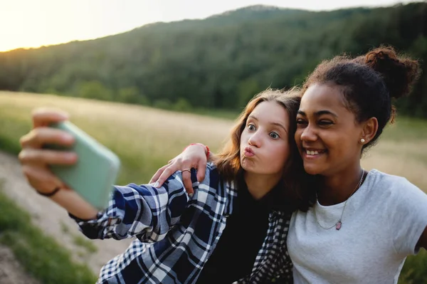 Pandangan depan gadis-gadis remaja teman luar ruangan di alam, mengambil selfie. — Stok Foto