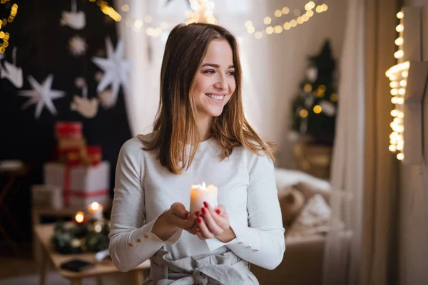 Portrait de jeune fille à l'intérieur à la maison à Noël, tenant une bougie. — Photo