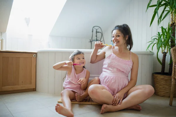 집안에 어린 딸이 있는 임신부가 집 화장실에서 이를 닦고 있는 모습. — 스톡 사진