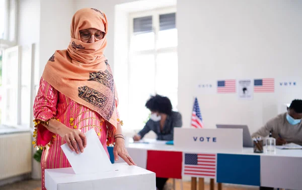 Une électrice islamique met son vote dans les urnes, les élections américaines et le coronavirus. — Photo