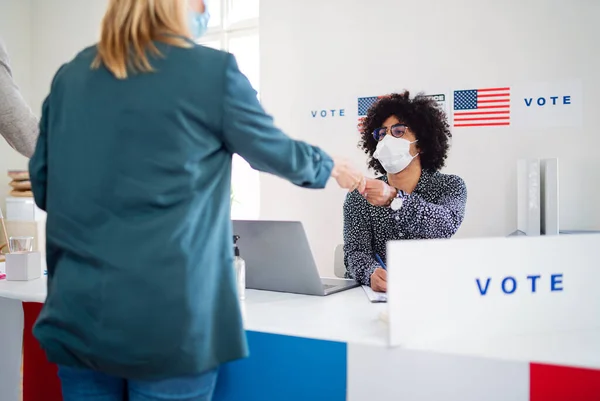 Personas con máscara facial votando en el lugar de votación, elecciones a EE.UU. y coronavirus. — Foto de Stock