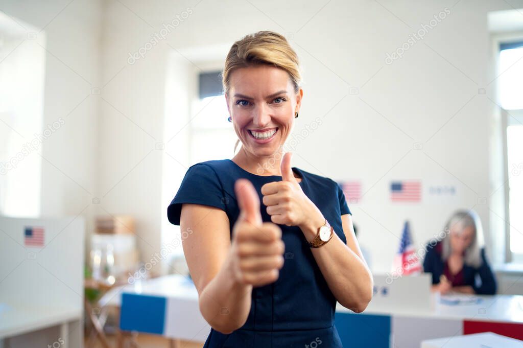 Portrait of happy woman voter with tumb up in polling place, usa elections concept.