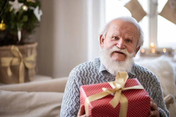 Front view of happy senior man with present box indoors at home at Christmas. — Stock Photo, Image