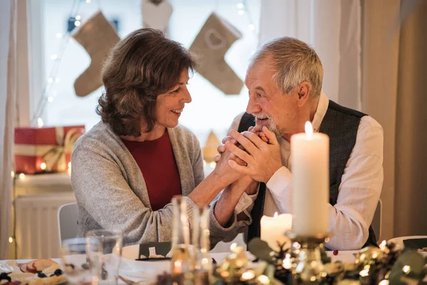 Szczęśliwa para seniorów siedząca w domu przy stole w święta, rozmawiająca. — Zdjęcie stockowe