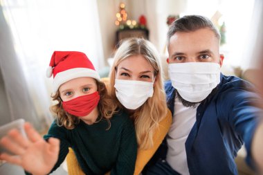 Noel 'de evde küçük kızları olan bir aile yüz maskeleriyle selfie çekiyor..