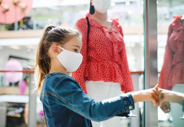 Alışveriş merkezinde yüz maskeli bir anne ve kız, koronavirüs konsepti..