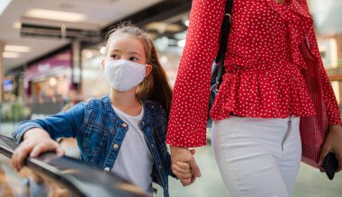 Alışveriş merkezinde yüz maskeli bir anne ve kız, koronavirüs konsepti..