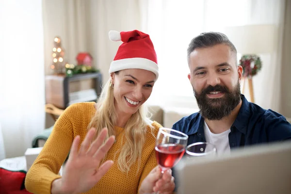 Vue de face du couple heureux à l'intérieur à la maison à Noël, avoir un appel vidéo avec la famille. — Photo