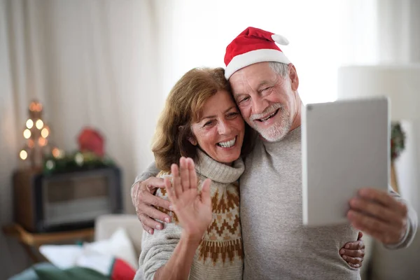 Front view of senior couple with face masks indoors at home at Christmas, taking selfie. — Stock Photo, Image