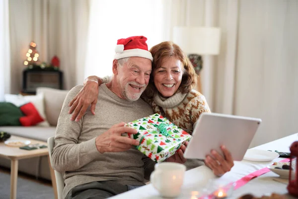 Vista frontal do casal sênior dentro de casa no Natal, tendo videochamada com a família. — Fotografia de Stock