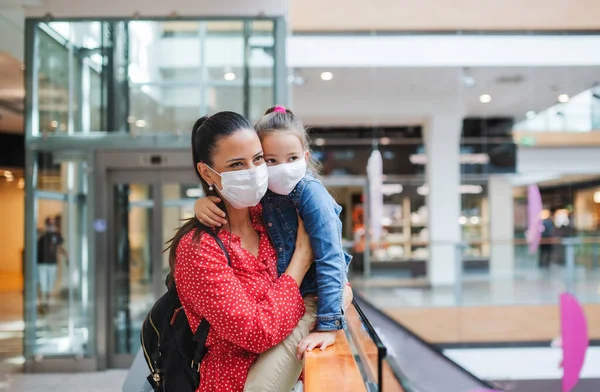 Мати і дочка з маскою для обличчя, що стоїть в приміщенні в торговому центрі, концепція коронавірусу . — стокове фото