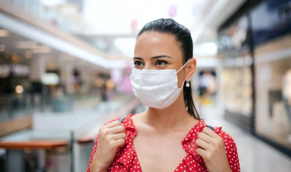 Женщина в маске для лица, стоящая в помещении торгового центра, коронавирусная концепция. — стоковое фото