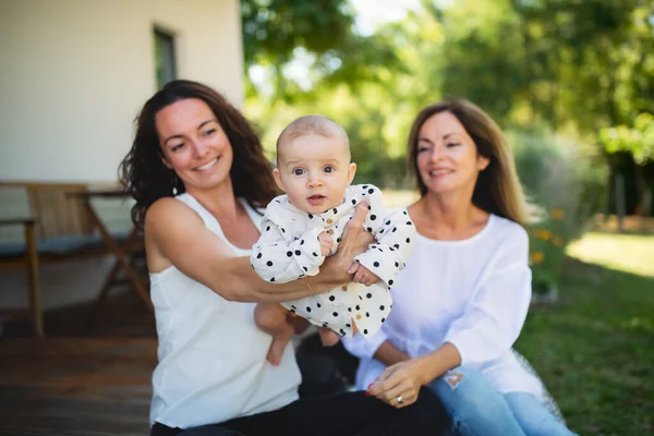 Mulher com filha e neta bebê descansando ao ar livre no quintal. — Fotografia de Stock