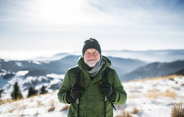 Porträt eines älteren Mannes, der in schneebedeckter Winternatur steht und in die Kamera blickt. — Stockfoto