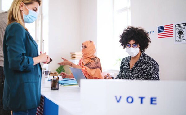 People with face masks voting in polling place, usa elections and coronavirus.