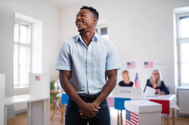 Afro-Amerikalı adam anketlerde gülüyor, ABD seçimleri.