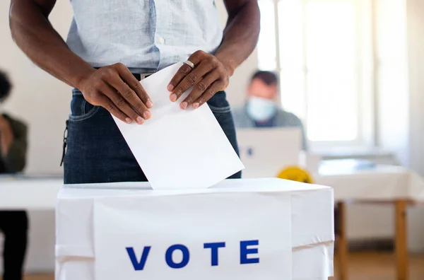 Homem afro-americano irreconhecível colocando seu voto na urna, eleições nos EUA e coronavírus. — Fotografia de Stock