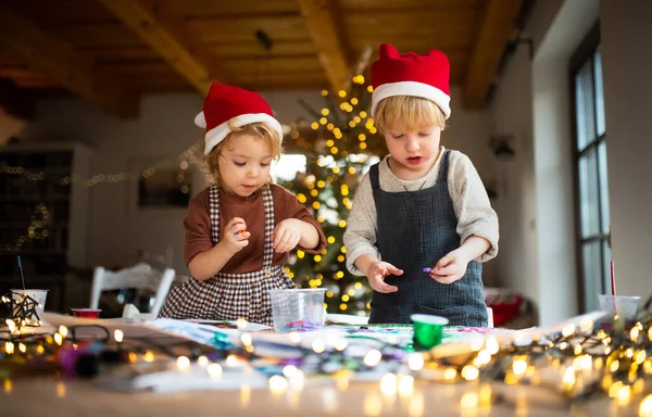 Retrato de menina e menino dentro de casa no Natal, fazendo arte e artesanato. — Fotografia de Stock