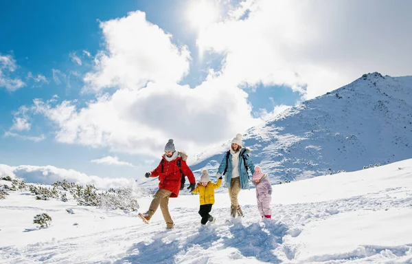 Anne ve baba kışın iki küçük çocukla karda yürüyorlar.. — Stok fotoğraf