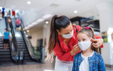 Yüzü maskeli anne ve kız alışveriş merkezinde kapalı duruyor, koronavirüs konsepti..