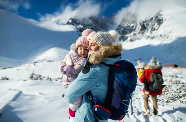 Mutter mit glücklicher kleiner Tochter steht in winterlicher Natur und ruht sich aus. — Stockfoto