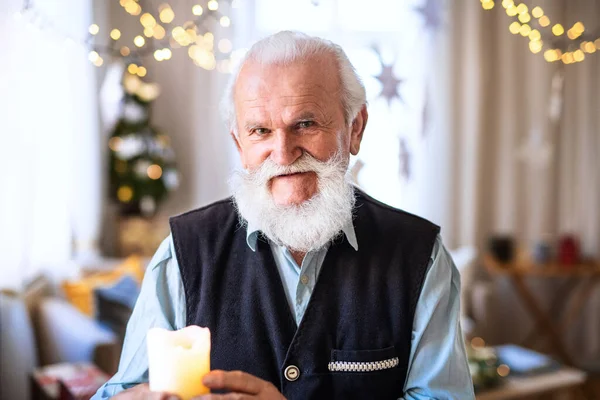 Vista frontale di felice uomo anziano con candela al chiuso a casa a Natale. — Foto Stock