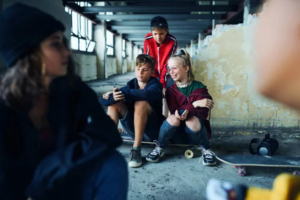 Grupo de adolescentes pandilla sentados en el interior de un edificio abandonado, utilizando teléfonos inteligentes. —  Fotos de Stock