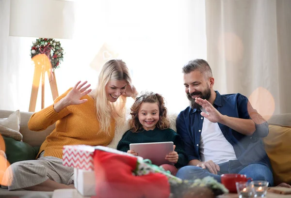 Família com filha pequena dentro de casa no Natal, tendo videochamada. — Fotografia de Stock