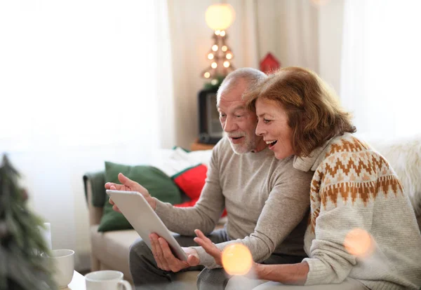 Vista lateral de pareja mayor en casa en Navidad, teniendo videollamada con la familia. —  Fotos de Stock