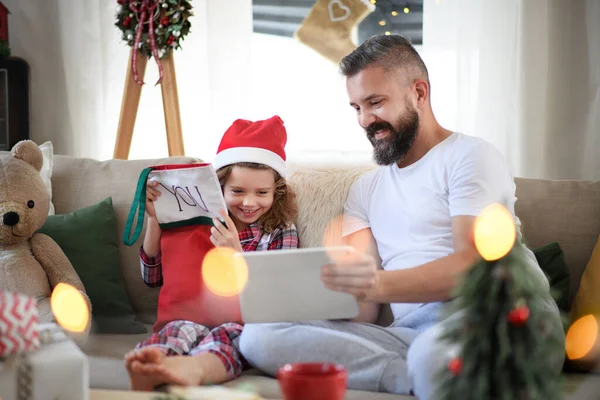 Ojciec z małą córeczką w domu w Boże Narodzenie, używając tabletu. — Zdjęcie stockowe