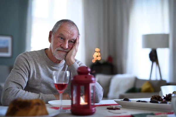 Μοναχικός ηλικιωμένος άνδρας με κρασί κάθεται στο τραπέζι σε εσωτερικούς χώρους τα Χριστούγεννα, έννοια της μοναξιάς. — Φωτογραφία Αρχείου