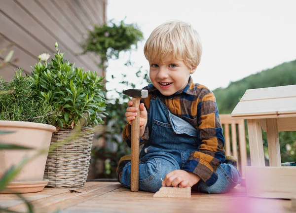 Portrét malého chlapce venku na stole výstavba ptačí budky, diy projekt. — Stock fotografie