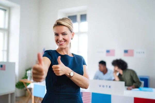 Portrait of happy woman voter with tumb up in polling place, usa elections concept.