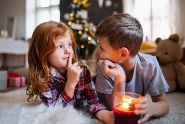 Noel 'de evde mum taşıyan küçük bir kız ve oğlan sessiz bir jest yapıyor..