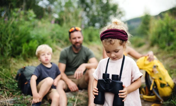 Familie mit kleinen Kindern wandern im Sommer draußen in der Natur, sitzen und ausruhen. — Stockfoto