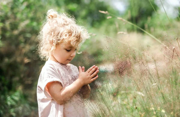 Portret małej dziewczynki na świeżym powietrzu w letniej przyrodzie, trzymającej trawę. — Zdjęcie stockowe